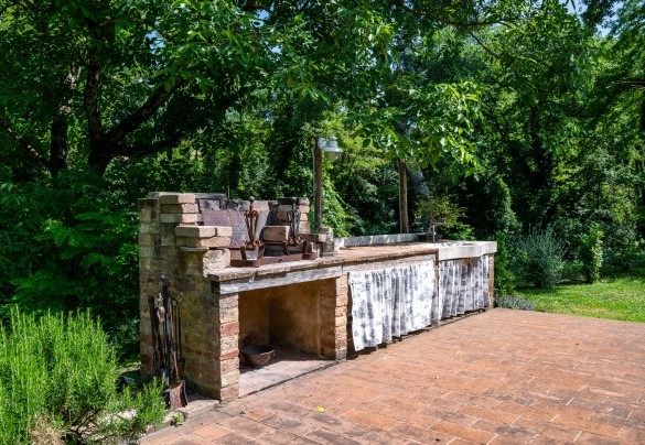 Barbecue in muratura con lavabo e piani di lavoro di fronte alla pergola dell’annesso - Il Molinaccio