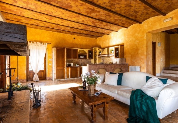 La grande sala con camino suddivisa in soggiorno-pranzo con cucina open-space al piano terra nel casale A - Il Poderuccio