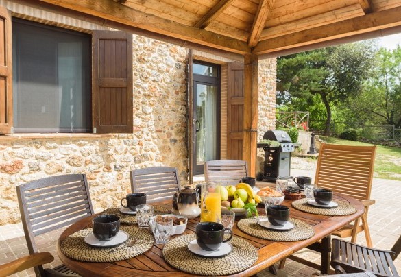 Davanti alle porte finestre che aprono sulla cucina si trova la zona pranzo all’aperto, attrezzata con un gazebo e arredata con tavolo e sedie da giardino – L’Ovile 