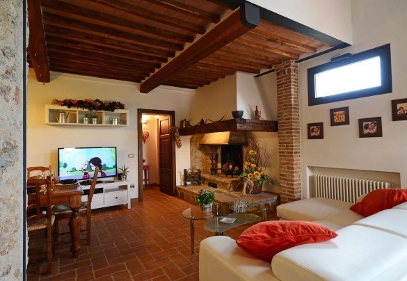 Comfortable sofa and satellite TV around the fireplace in the living area on the ground floor - La Capanna di Franca 6+2