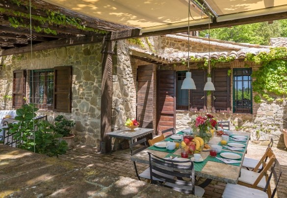 The outdoor dining area under the pergola, set up with table and chairs - La Cerqua