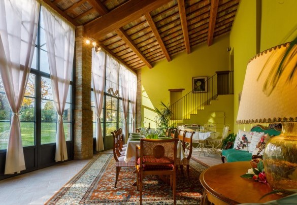 The veranda is furnished with tables, chairs and a sofa - La Tana del Ghiro