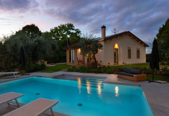 La piscina illuminata e sullo sfondo la graziosa villa - La Villanella