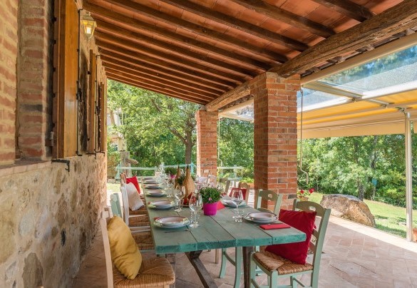 Il portico fronte piscina, arredato con living ed area pranzo che si apre sul giardino e consente una fruizione comoda e completa dell’area - Le Bandite 