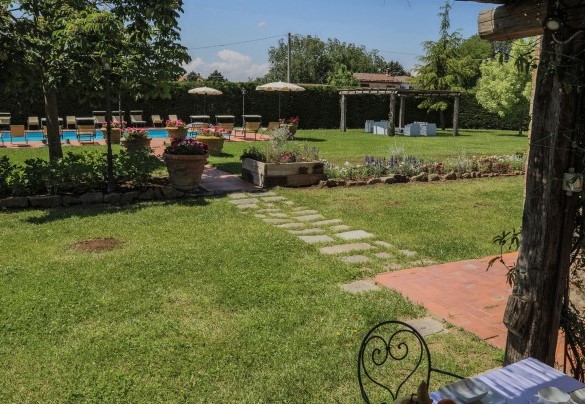 La distesa pianeggiante di prato all'inglese, racchiusa da un'alta siepe e ricca di piante ad alto fusto - Le Caselle