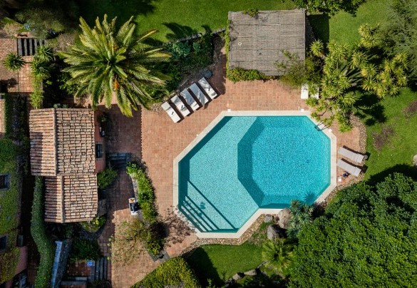 La zona piscina con un living sotto il pergolato e la struttura che ospita lo spogliatoio e la cucina esterna - Linera