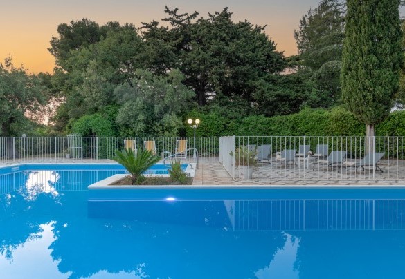 Piscina circondata da alberi e piante molto curate e completamente recintata – Masseria Profilo
