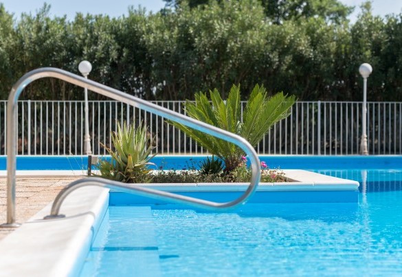 Piscina circondata da alberi e piante molto curate e completamente recintata – Masseria Profilo