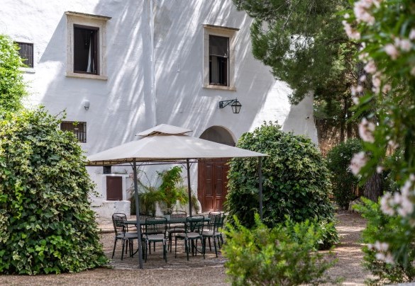 The area in front of the entrance to the house is equipped with a gazebo and table, surrounded by colourful plants and flowers – Masseria Tarsia Incuria