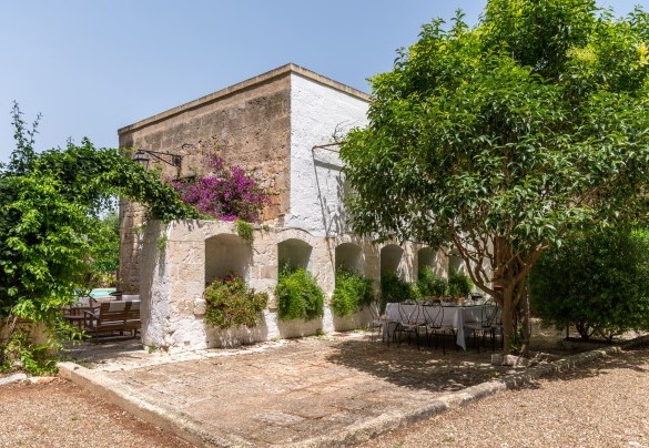 A picturesque arch adorned with vines and flowers leads to the pool area – Masseria Tarsia Incuria