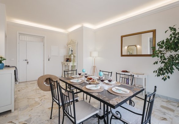 Dall'ingresso di questo attico situato al quinto piano, si accede in un luminoso e largo open space con finestre vista mare che accoglie la cucina e l’area pranzo. Nova Domus