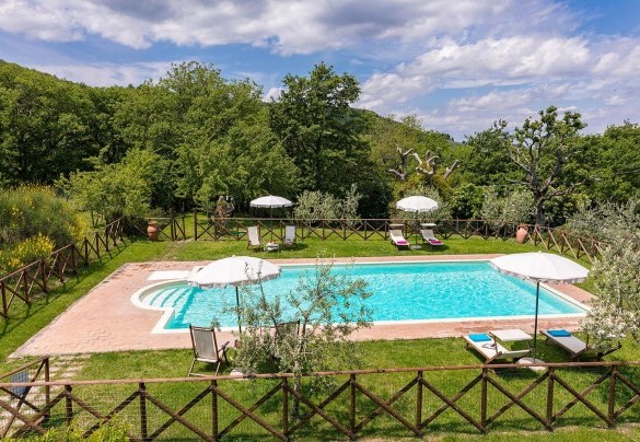 Solarium bordered by hedges and bushes and equipped with sunbeds, deckchairs, small tables and sun umbrellas – Podere Bagnolo 8