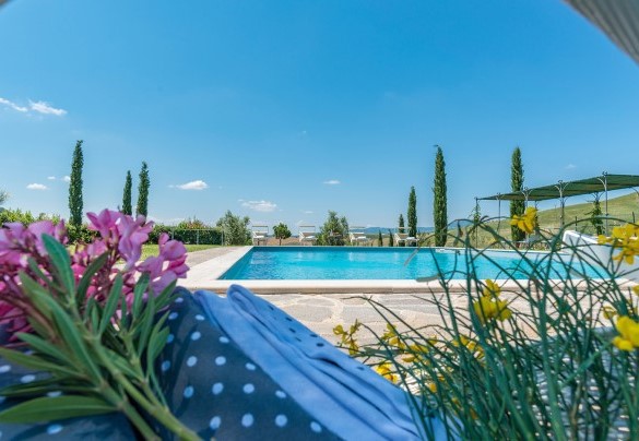Una larga superficie in pietra di porfido circonda la piscina - Podere Collelungo