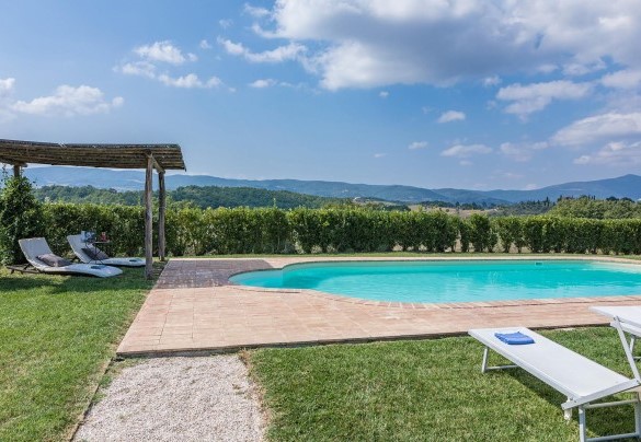 La vasca è inserita in un’ampia area solarium dalla superficie pianeggiante in parte pavimentata in cotto e in parte coltivata a prato, dove trovano posto lettini, una pergola ombreggiante e la doccia solare – Podere di Salci
