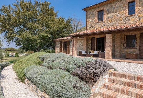 Il curato giardino che si sviluppa attorno al casale per circa 3000 metri quadrati, tra superfici a ghiaino e prato, vivacizzato da bordure di lavanda, aromatiche, arbusti e cespugli di rose bianche – Podere di Salci