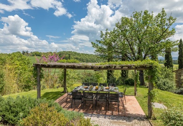 Large paved pergola with a dining area furnished with table and chairs - Podere Fabbrica