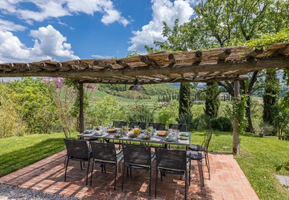 La zona pranzo esterna sotto la pergola, allestita con tavolo, sedie e barbecue mobile - Podere Fabbrica 