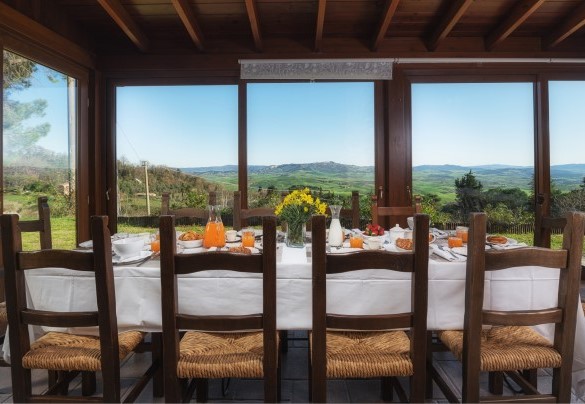 Comfortable dining table in the glass-enclosed veranda with a view on the city of Volterra – Podere Il Chiesino
