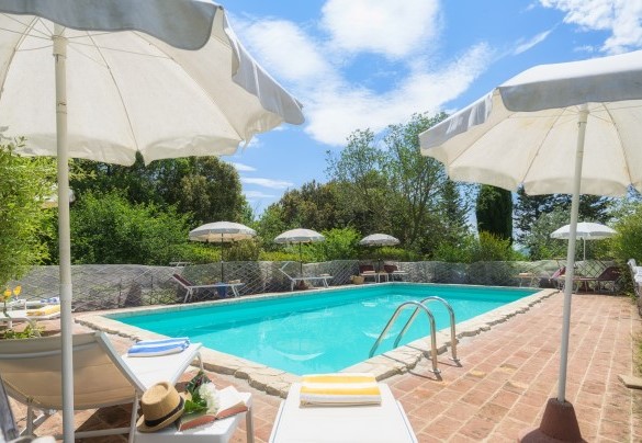 La piscina con area solarium dotata di ombrelloni e lettini – Podere Orcio