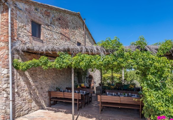 Il grande porticato, in prossimità degli ingressi principali, è arredato con divani e tavoli per colazioni all’aperto – Podere San Ansano 
