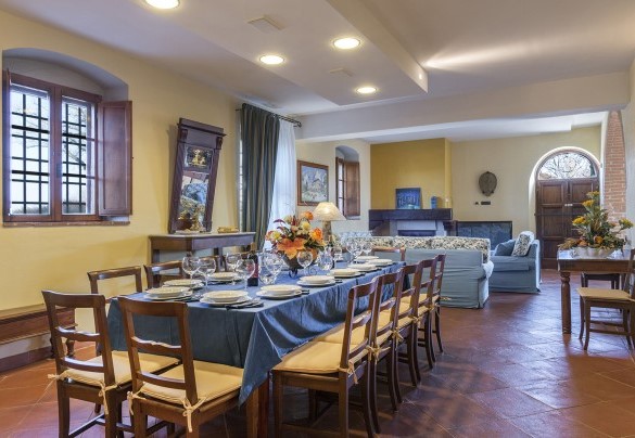 Il living, dotato di aperture dirette sul giardino, organizzato con salotto, raccolto attorno ad un rustico camino e la zona pranzo - Podere Sant’Eugenio