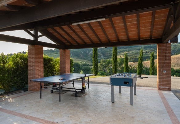 The shaded outdoor play area under a loggia with table football and a ping pong table – Podere Terranuova