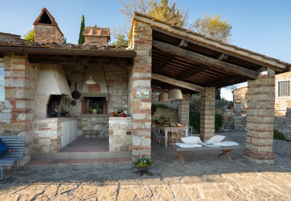 The spacious central courtyard houses a portico with dining table and an outdoor kitchen with stone barbecue and worktop – Poggio Novoli