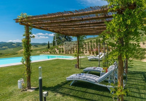 Piscina a sfioro con pergolato attrezzato con lettini e tavolini nella zona solarium in prato - Rosa dei Venti 8