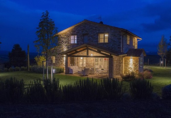 Il casale con portico arredato con tavolo e zona relax illuminato nelle ore serali – Rosa dei venti 8
