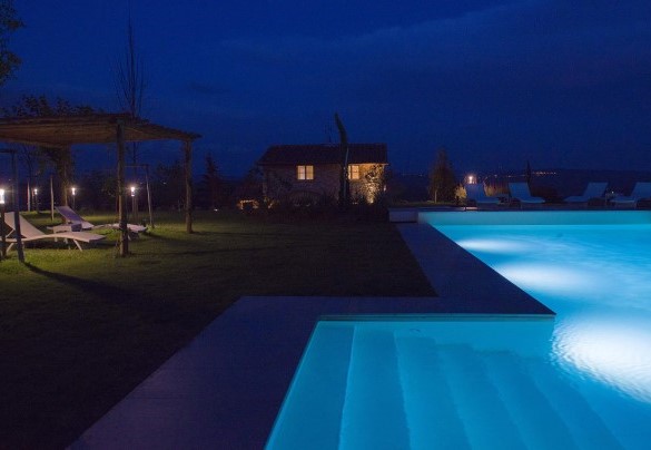 Piscina a sfioro e il casale illuminati nelle ore serali – Rosa dei venti 8