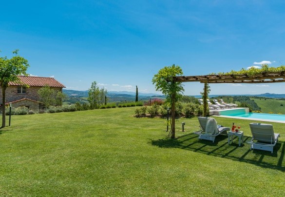 Zona solarium in prato con il pergolato attrezzato con lettini e tavolini verso il casale – Rosa dei Venti 8  
