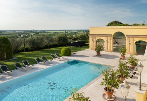 La piscina esterna è circondata da un ampio solarium arredato con lettini ed ombrelloni - Tenuta Bagni De' Consoli