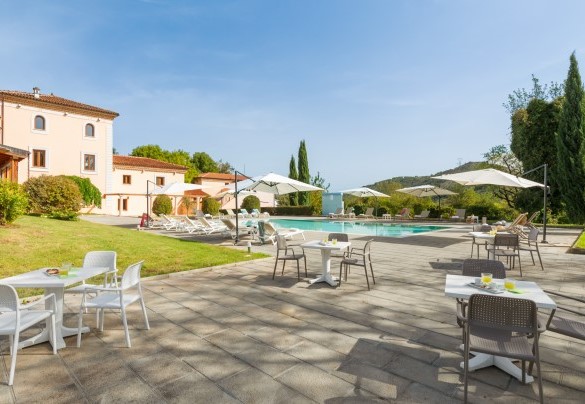Area solarium attrezzata con lettini, ombrelloni, tavoli con sedie e doccia esterna - Tenuta Esdra