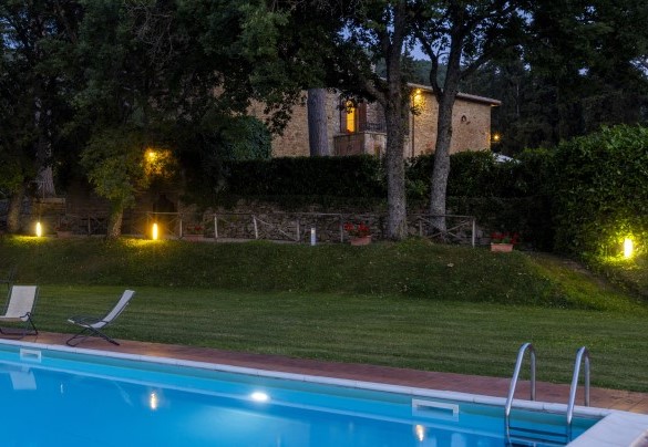 La piscina illuminata e sullo sfondo la casa - Torre di Paciano