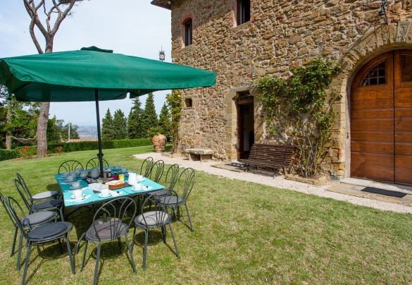 The outdoor dining area, set up with table, chairs and umbrella  - Torre di Paciano