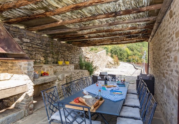 The upper floor pergola is fully equipped with a sitting area, a table, and a stone-built barbecue - Torre Ginestre