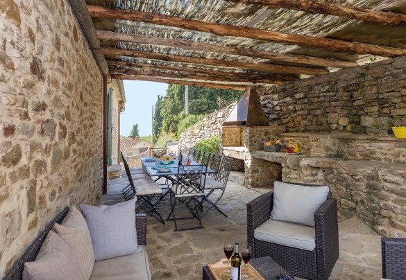 The upper floor pergola is fully equipped with a sitting area, a table, and a stone-built barbecue - Torre Ginestre