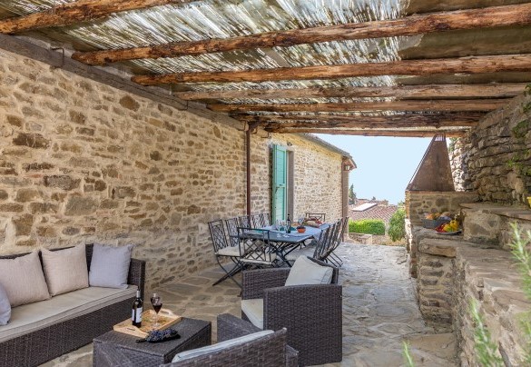 The upper floor pergola is fully equipped with a sitting area, a table, and a stone-built barbecue - Torre Ginestre