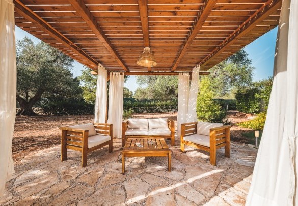 The wooden gazebo furnished with table and sofas for aperitifs at sunset -Trulli Biancapetra