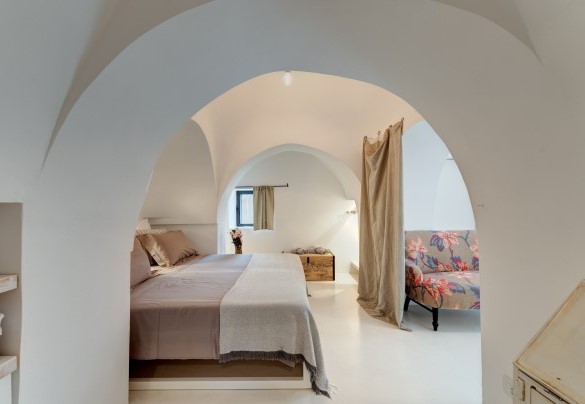 La camera matrimoniale n.2 nei trulli, è separata dalla zona giorno da un arco con tenda tipico di queste strutture - Trulli Santa Pazienza