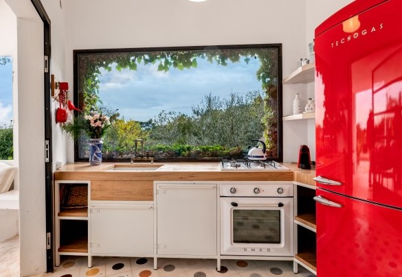 La cucina a vista della lamia principale gode di una ampia finestra con veduta sul verde– Trulli Santa Pazienza
