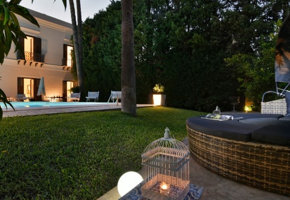  Il giardino pianeggiante circonda la piscina ed è composto da un prato puntellato da arbusti fioriti e qualche albero da frutto incluso un mango sotto il quale è posto un letto tondo con copertura ombreggiante - Villa Afrodite 