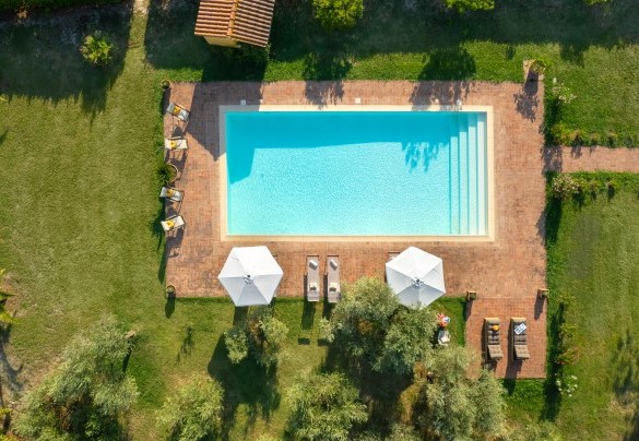 The solarium extends around the pool, partly paved in terracotta and partly in natural lawn, and is equipped with sunbeds and umbrellas – Villa Allodola