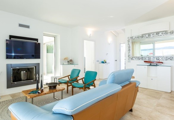 Zona salotto con divano, caminetto ornamentale e angolo Smart Tv - Villa Amar