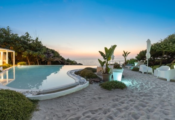 The swimming pool at sunset with a white sandy beach around it – Villa Ambra