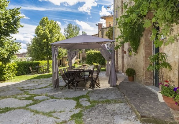 La zona antistante la villa è in lastre di pietra e prato ed è attrezzata con largo porticato, tavoli in legno, ombrelloni e un grande barbecue - Villa Angelini