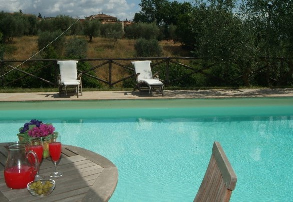 L’area piscina è circondata da pavimentazione in travertino toscano, è contornata da piante di olivo ed è attrezzata con lettini, sedie, tavoli in legno, ombrelloni e doccia esterna - Villa Angelini