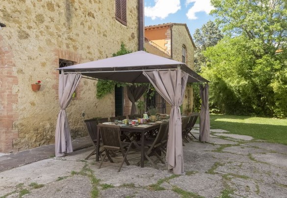 Un portico ombreggia un lungo tavole con sedie- Villa Angelini