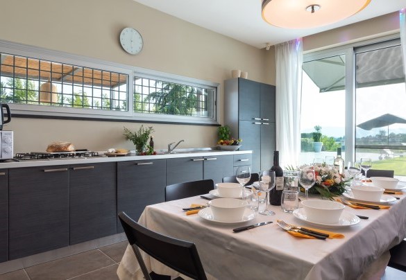 The kitchen, efficient and functional, furnished with table and chairs and direct access to the outside – Villa Atmosfere