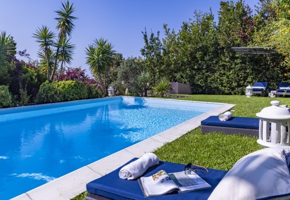 The swimming pool is equipped with sun loungers arranged along the lawn solarium that surrounds it and a shading pergola at the corner - Villa Bambù